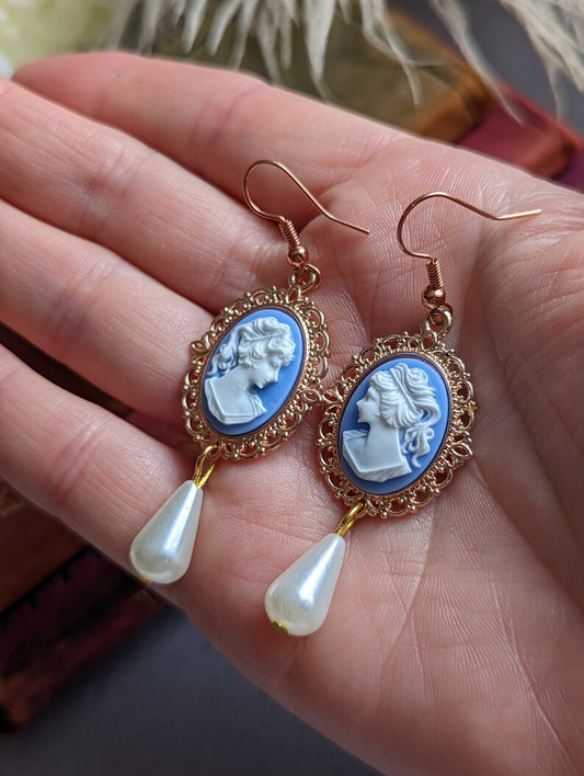Blue cameo pearl drop earrings in lacy 14k rose gold plated settings being held in a hand