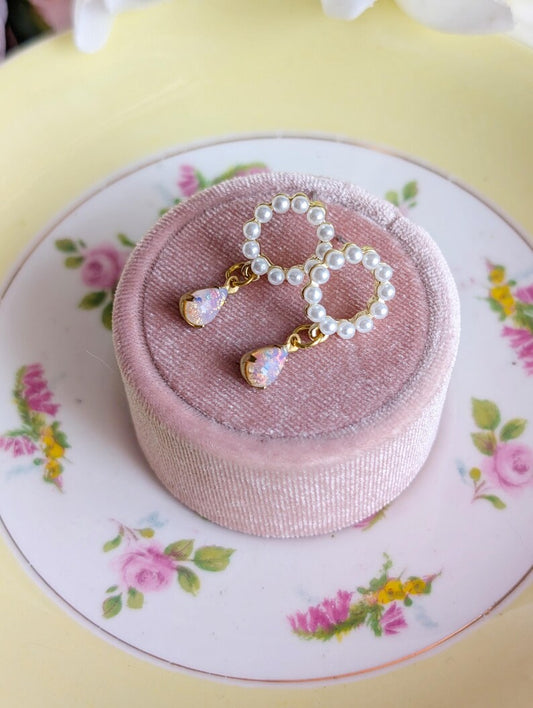 Handmade Pearl and Fire Opal earrings on a pink jewelry box with a floral-patterned plate underneath