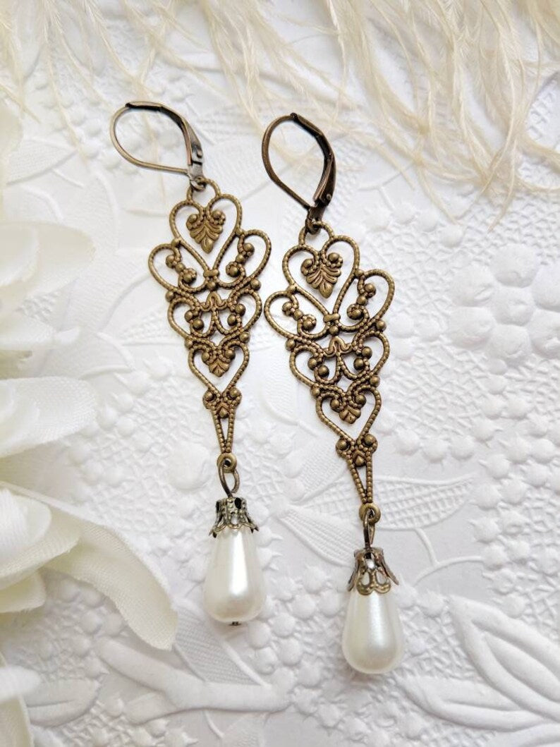 Ornate earrings with pearl drops on a textured white background
