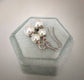Pair of ivory double pearl drop earrings with antiqued silver filigree bead caps,on a hexagonal green velvet stand