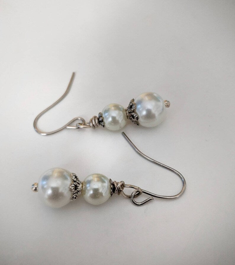Pearl earrings with silver hooks on a light gray background