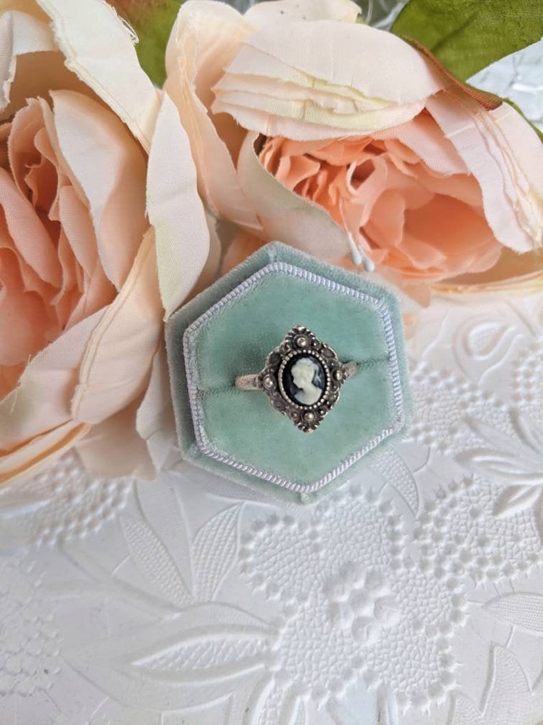 Vintage ring in a hexagonal box with pink flowers on a textured white surface