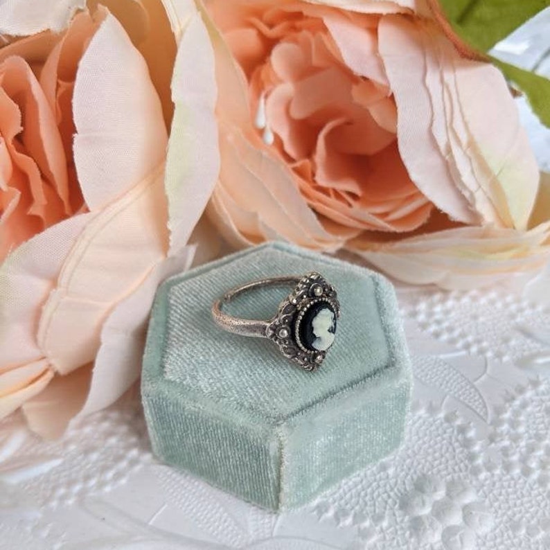 Greek Goddess Shield Cameo Ring - Antiqued Silver Brass Signet with an ivory on black cameo in a green box with pink flowers in the background