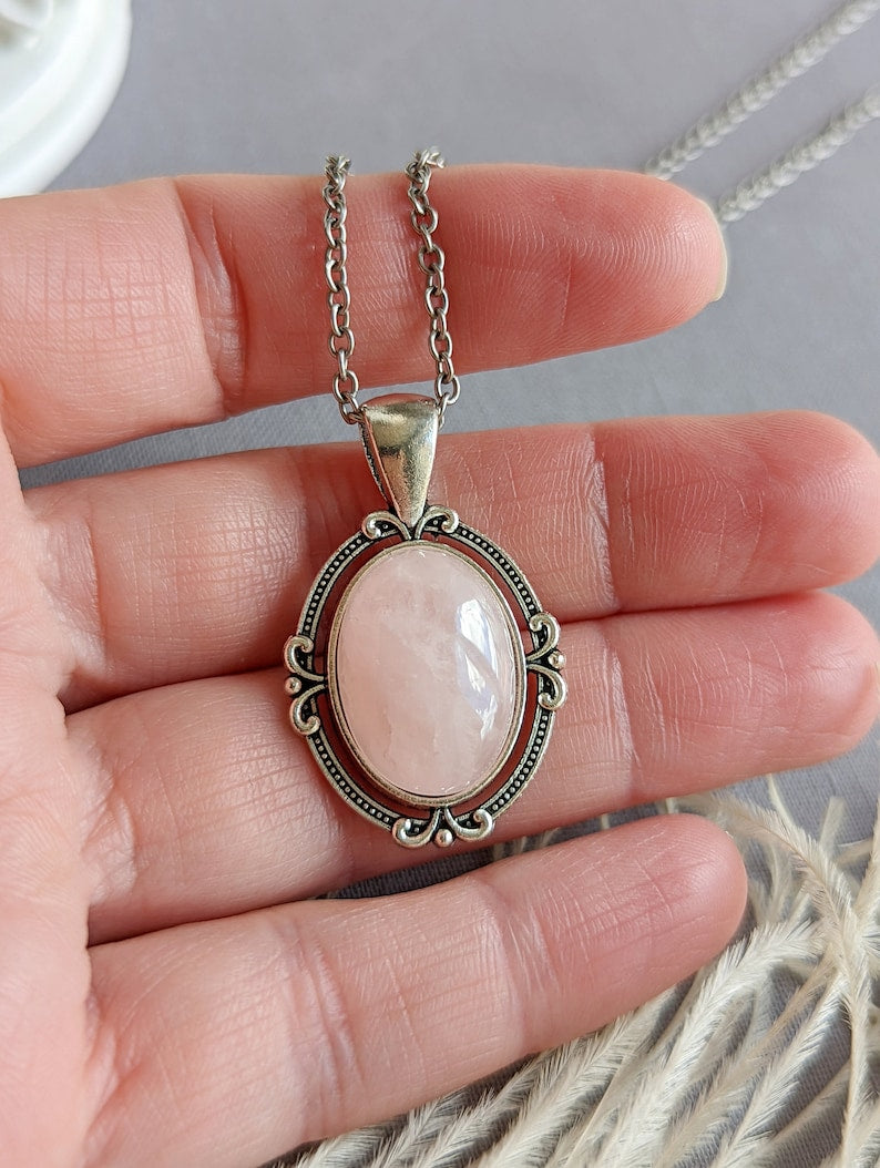Pale Pink Rose Quartz Crystal Necklace - Silver Flourish Pendant Setting held between fingers against a neutral background