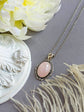 Pale Pink Rose Quartz Crystal Necklace - Silver Flourish Pendant Setting on a gray surface with flowers and feathers