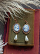 Blue cameo pearl drop earrings in lacy 14k rose gold plated settings on a textured surface.