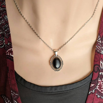 Black Obsidian Crystal Necklace - Silver Flourish Pendant Setting on a mannequin wearing a patterned garment.