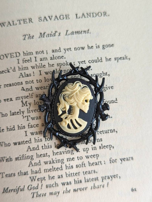 Gothic Black bramble brooch featuring a female skeleton cameo displayed on an open book with text