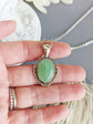 Green Aventurine Crystal Necklace - Silver Flourish Pendant Setting held by a hand with a blurred background