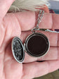 Open Silver round floral etched locket necklace by Papillion Era held in a hand