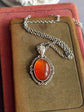 Red Carnelian Crystal Necklace - Silver Flourish Pendant Setting on a brown velvet surface