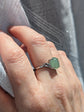 Close-up of a hand wearing a Natural Green Aventurine Solitaire Ring -Sterling Silver - Handmade Gemstone Jewelry - Made in Toronto with a blurred background