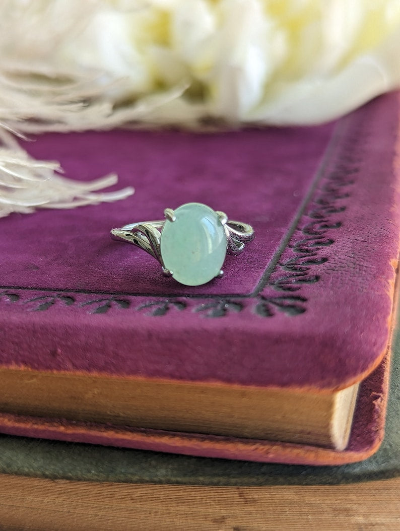 Natural Green Aventurine Solitaire Ring - Sterling Silver - Handmade Gemstone Jewelry - Made in Toronto on a purple leather-bound book with feathers in the background