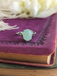Natural Green Aventurine Solitaire Ring - Sterling Silver - Handmade Gemstone Jewelry - Made in Toronto on a purple leather-bound book with feathers in the background