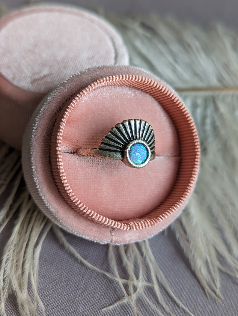 Art Deco Fan Ring with Iridescent Blue Opal - Silver Finish in a pink velvet ring box on a textured surface