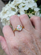 Hand wearing a Pink Rose Cameo Ring - Gold Vermeil Sterling Silver Adjustable Band, set against a background of white flowers.