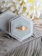 Matte gold cameo ring with single loop shoulder detail in a hexagonal green velvet box against a floral background