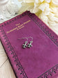 Fleur de Lis Earrings - Pewter French Lily Flower - Victorian Jewelry displayed on a purple poetry book, surrounded by white flowers.