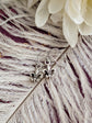 Fleur de Lis Earrings - Pewter French Lily Flower - Victorian Jewelry on a feather with white flowers in the background