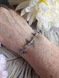 Silver Swallow Bird Bracelet: Dainty Trio Jewelry, Minimalist Style on a wrist, with white flowers in the background