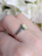 Side view of a 925 Sterling Silver Celtic Knot Cameo Ring - Heritage Style Jewelry with an ivory on green cameo on a hand with a blurred floral background