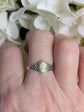 925 Sterling Silver Celtic Knot Cameo Ring - Heritage Style Jewelry with an ivory on green cameo on a finger against a white flower background