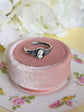 925 Sterling Silver Celtic Knot Cameo Ring - Heritage Style Jewelry with an ivory on black cameo on a pink velvet cushion, surrounded by white flowers.