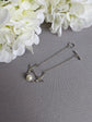 Silver Swallow Bracelet with Glass Pearl and Toggle Clasp on a gray surface with white flowers.