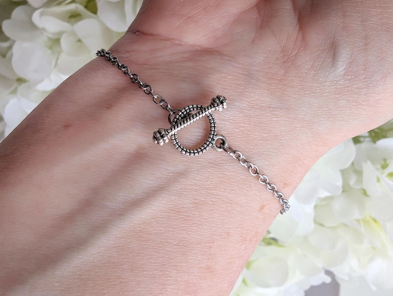 Close up of toggle clasp on a wrist with a floral background