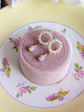 Handmade Pearl and Fire Opal earrings on a pink jewelry box with a floral-patterned plate underneath