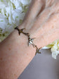 Bronze Swallow Bracelet on a wrist against a white floral background