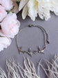 SIlver Swallow Bracelet, Dainty Trio of Flying Birds, Vintage Jewelry on a gray surface with pink and white flowers and dried grasses.