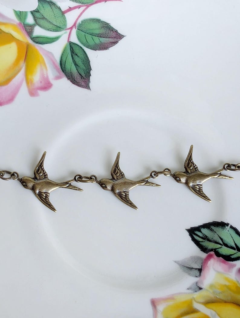Close-up of a brass bird-shaped bracelet on a floral-patterned background