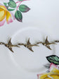 Close-up of a brass bird-shaped bracelet on a floral-patterned background