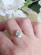 Hand wearing a Gold Vermeil Blue Rose Ring - 925 Sterling Silver - Victorian Floral Jewelry against a white flower background