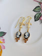 Handmade ivory on black cameo earrings with gold Fleur de Lis connectors and cognac Austrian crystals on a floral teacup.