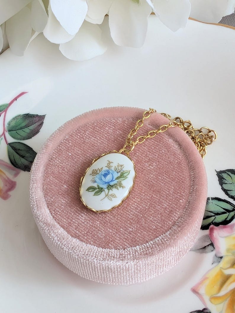 Blue Rose Vintage Porcelain Necklace - 1980s Limoges Style on a pink velvet cushion, floral background