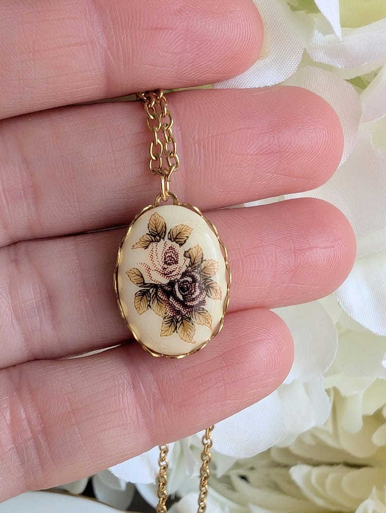 Two-tone Pink Floral Bouquet Necklace - Vintage 1980s Ivory Porcelain Cabochon pendant held between fingers against a floral background