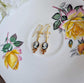 Handmade ivory on black cameo earrings with gold fleur de lis connectors and cognac Austrian crystals on a floral teacup.
