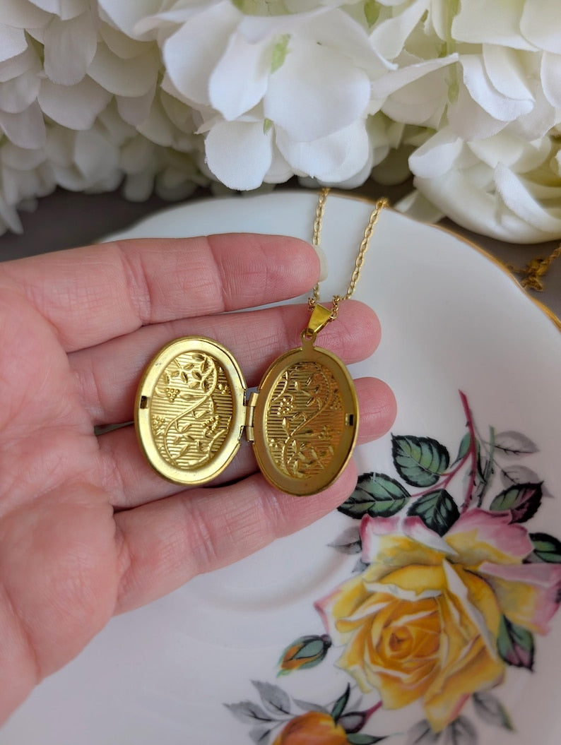 Gold locket held by a hand with a floral background