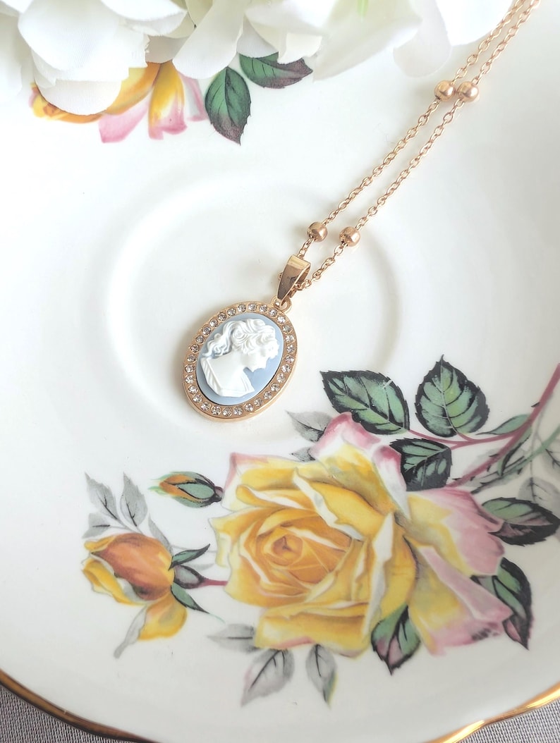 Handmade Gold Blue Lady Cameo Necklace with CZ Halo on Station Chain on a floral plate
