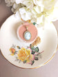 Handmade Gold Blue Lady Cameo Necklace with CZ Halo on Station Chain with a pink box on a decorative plate with floral design