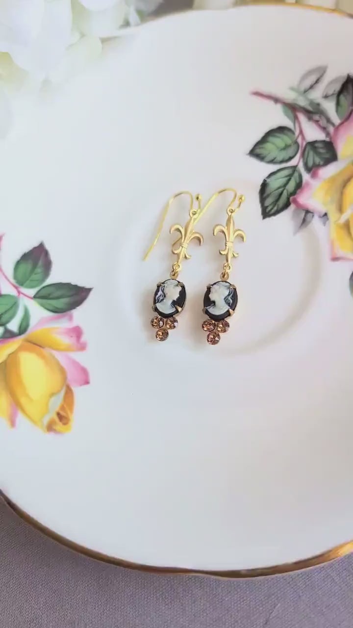Handmade ivory on black cameo earrings with gold Fleur de Lis connectors and cognac Austrian crystals on a floral teacup.