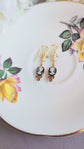 Handmade ivory on black cameo earrings with gold Fleur de Lis connectors and cognac Austrian crystals on a floral teacup.