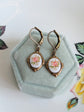 Pink Floral Porcelain Cabochon Earrings - Art Deco Frame - Victorian Style in a hexagonal green velvet box with floral designs in the background.