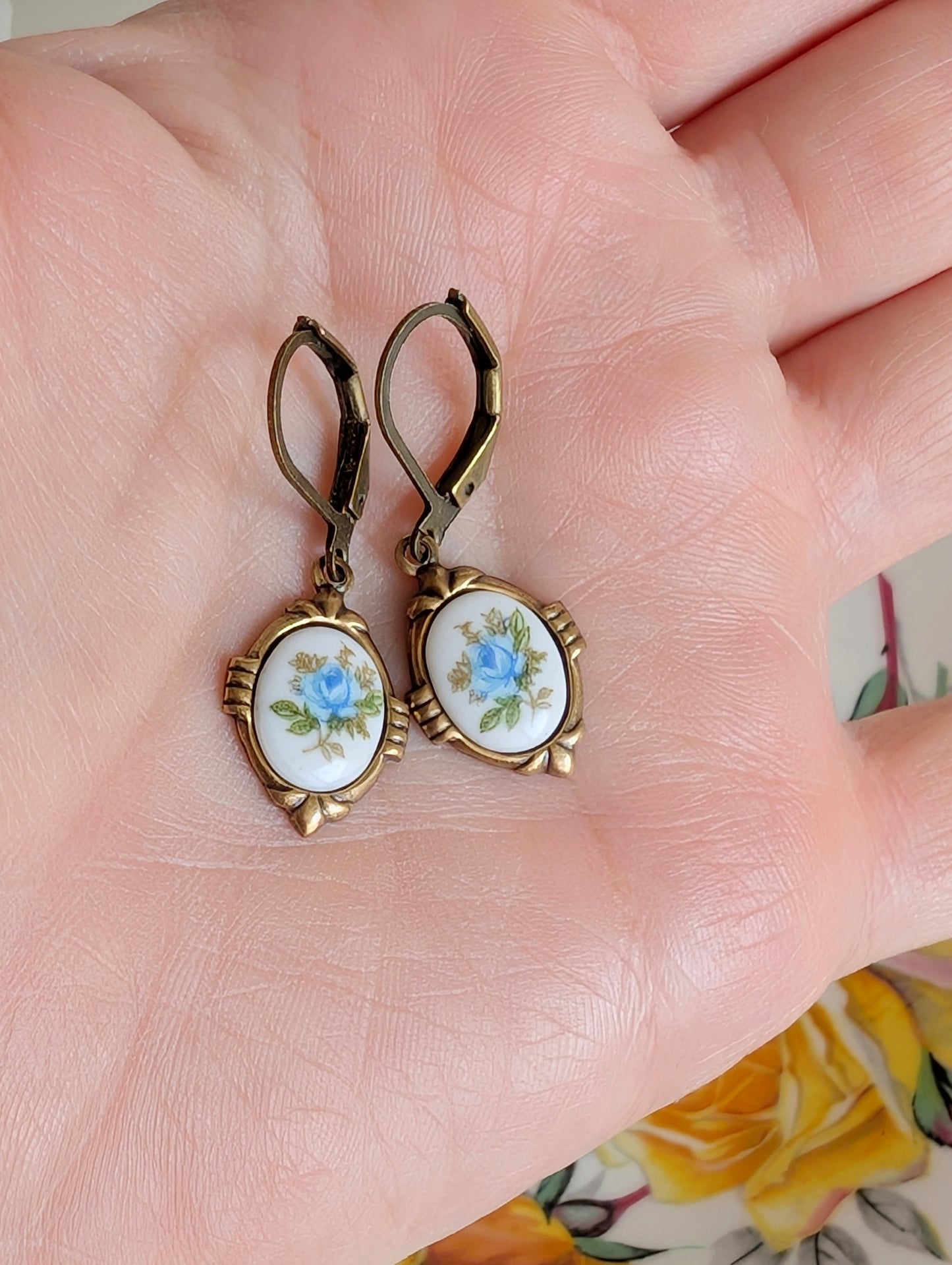 Blue Floral Porcelain Cabochon Earrings - Art Deco Frame - Victorian Style held in a hand.