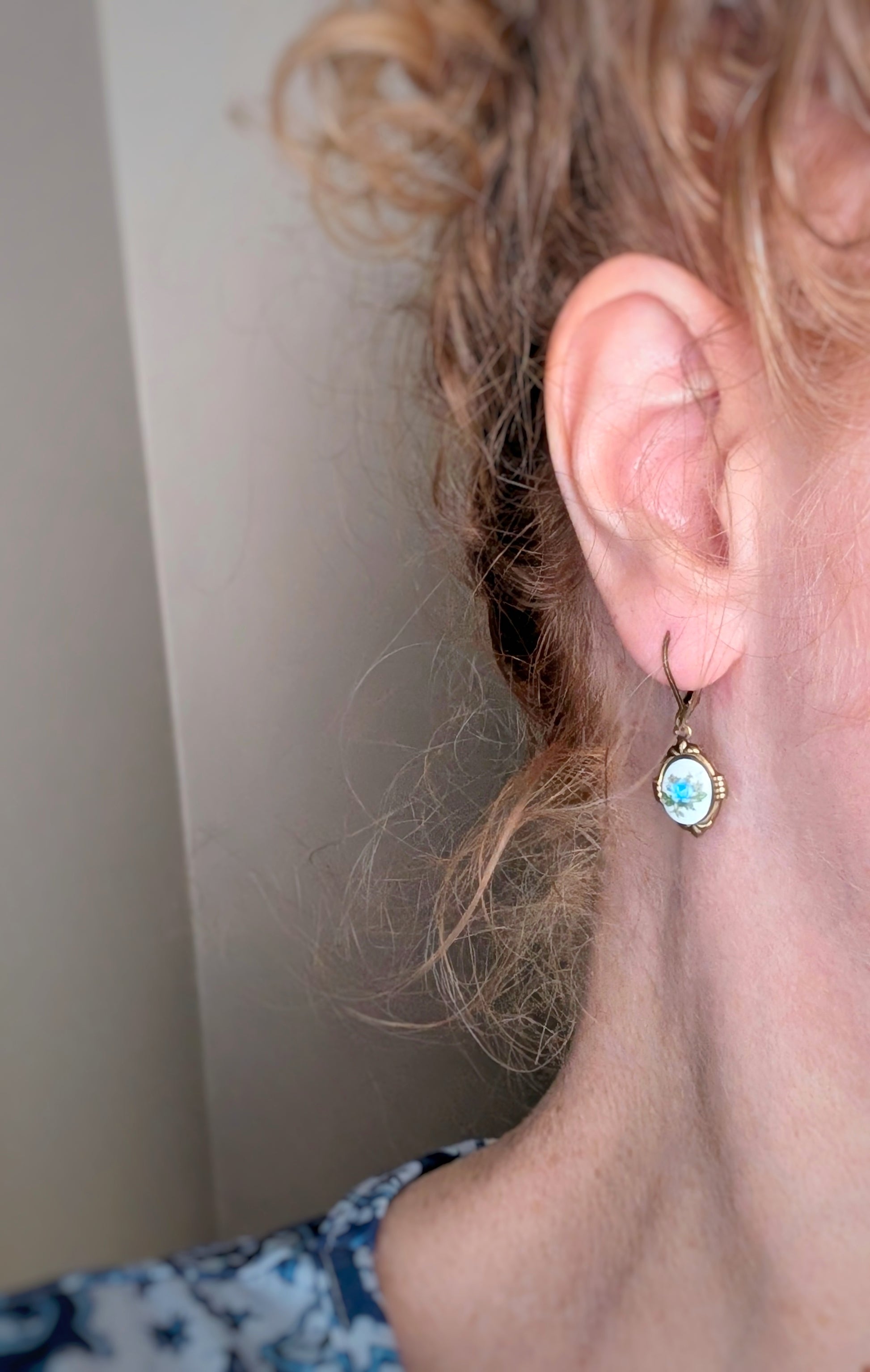 Close-up of an ear wearing a Blue Floral Porcelain Cabochon Earring - Art Deco Frame - Victorian Style